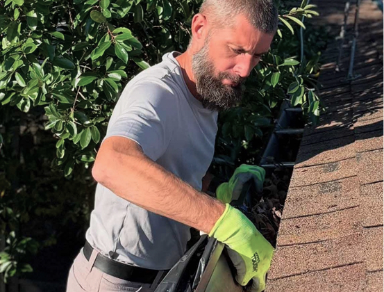 man-cleaning-autumn-leaves-from-roof-gutter