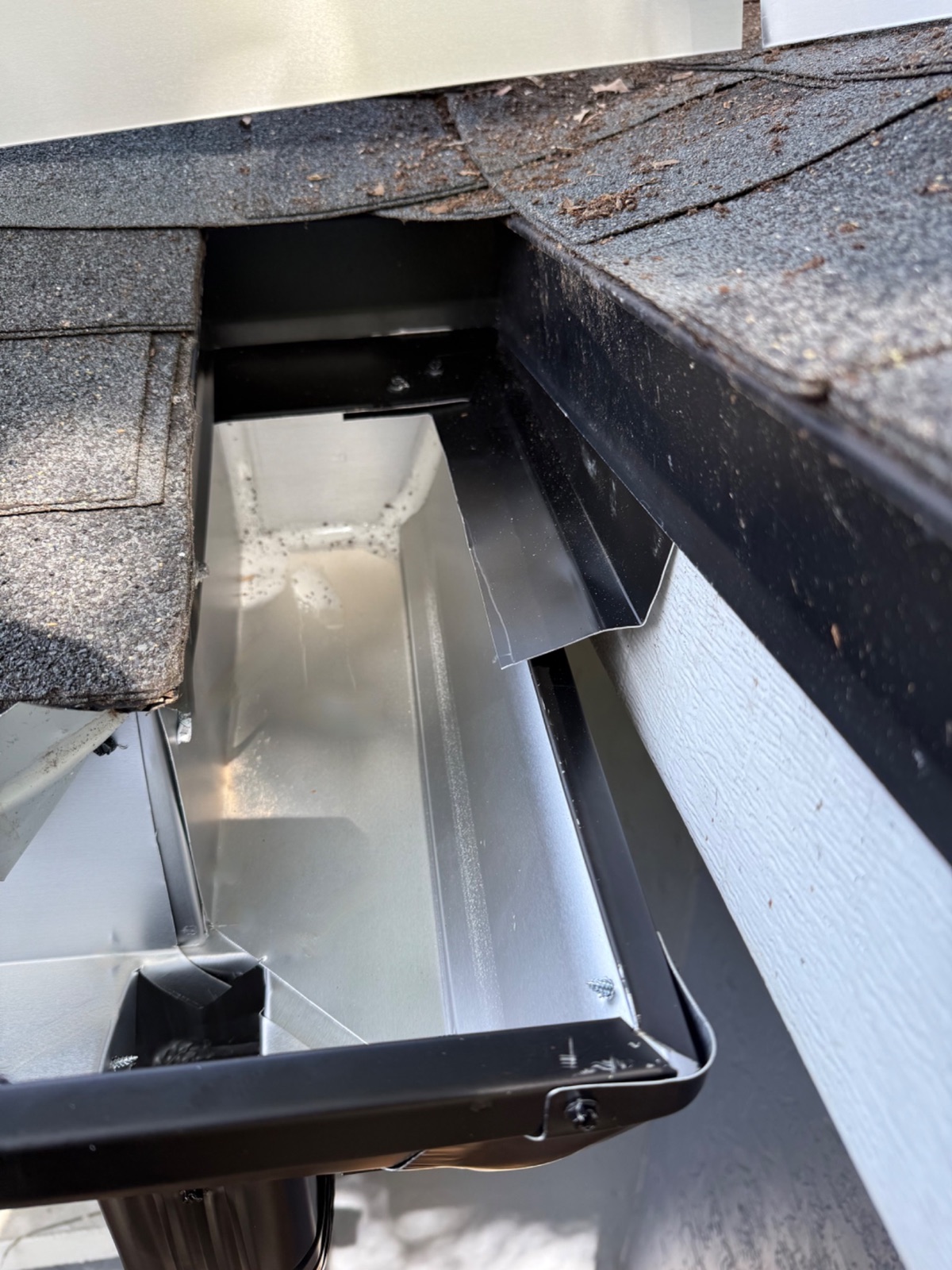 Custom flashing directing roof-valley runoff into a new gutter